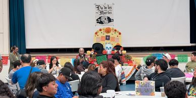 Students and some teachers gathering in the cafeteria sitting down at different tables doing art
