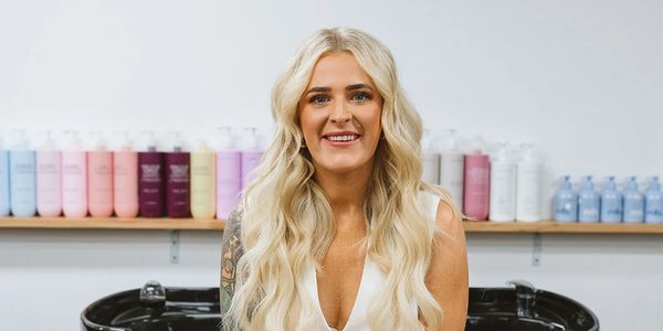 Smiling woman with long blonde hair in a salon setting.