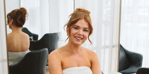 Smiling woman in a towel sitting in a salon with mirrors.