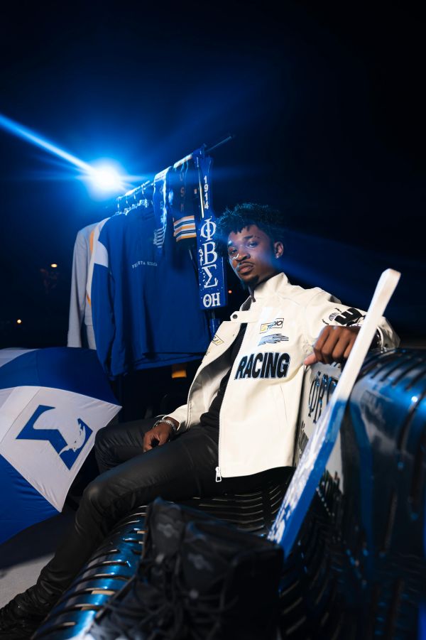 Man sitting on a bench with blue and white clothing and umbrella.