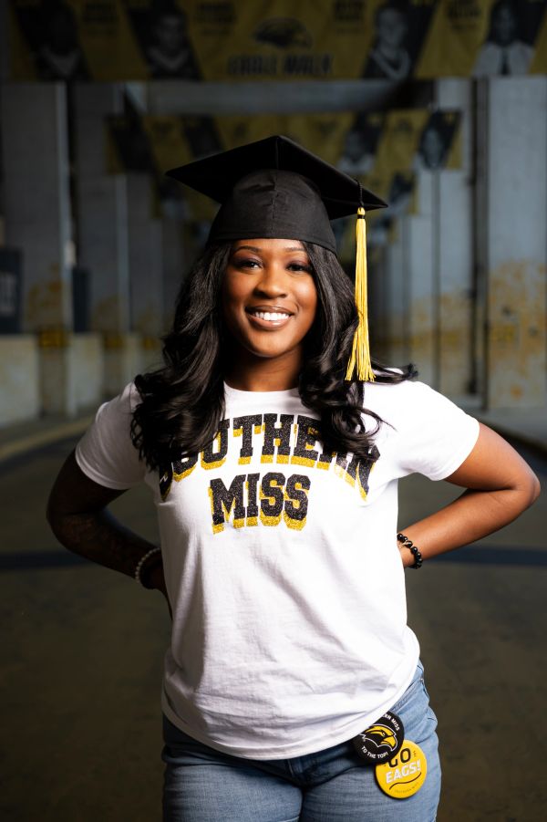 Smiling graduate in Southern Miss shirt and cap.