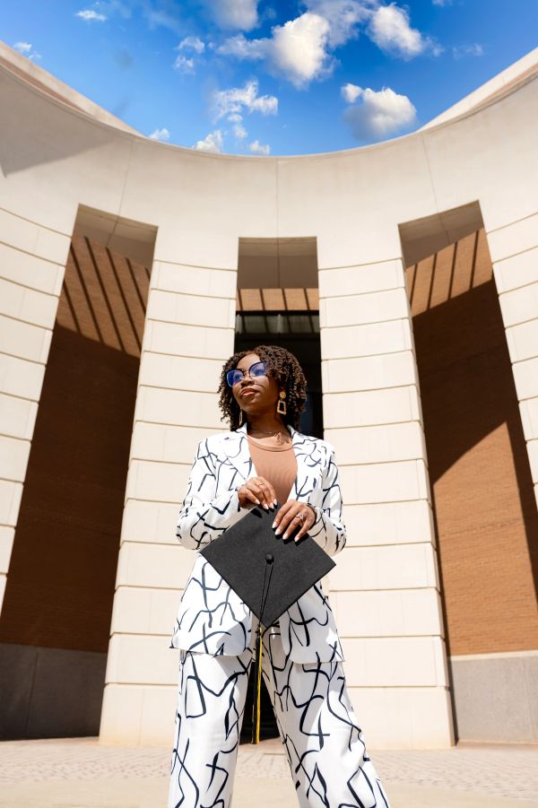 Confident graduate standing outside a building on a sunny day.