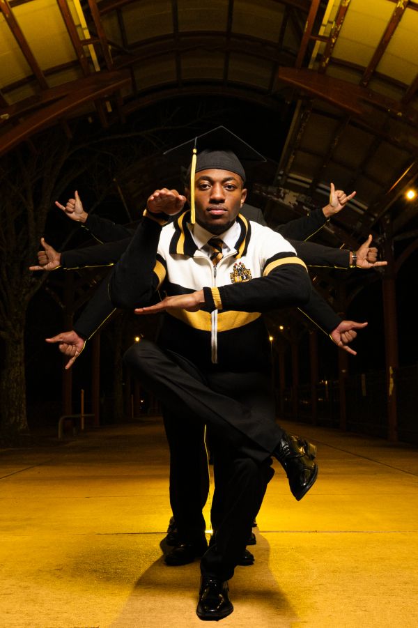 Graduate in a creative martial arts pose with impromptu multiple arms effect.