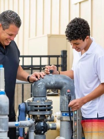 Father enjoying training his young son to understand and operate pool equipment