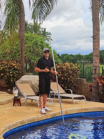 Happy pool technician smiling by residential swimming pool in Kapolei while doing shaka sign