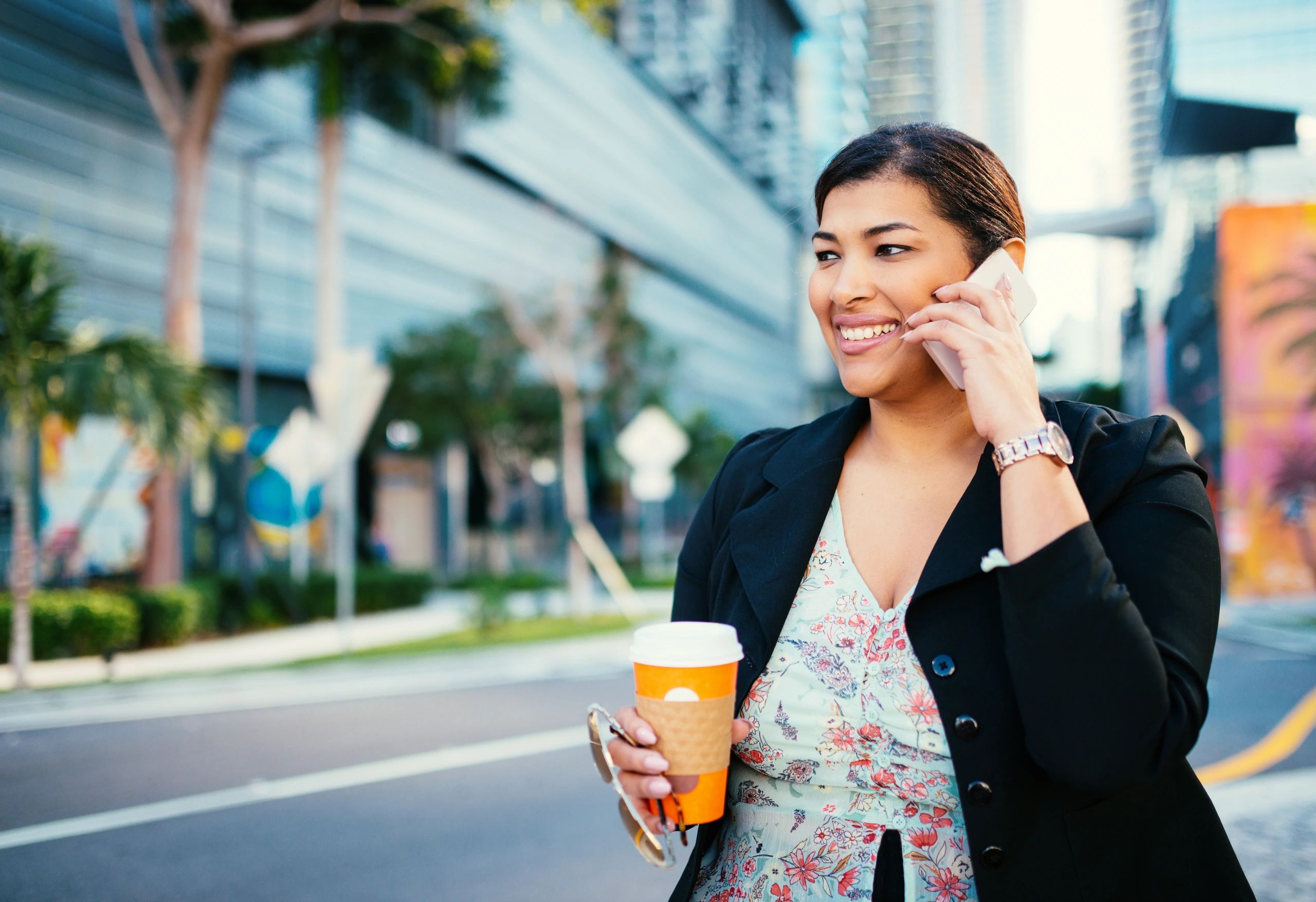 Successful business owner talking to a customer on her cell phone as she walks to her office