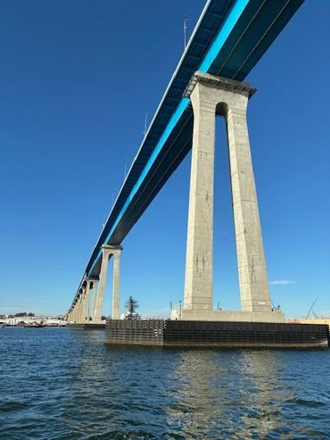 A large blue bridge spanning over water under a clear sky.