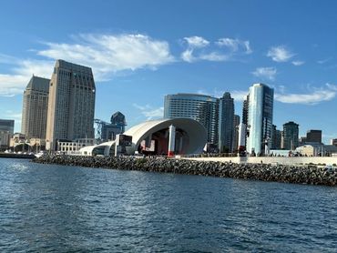 Waterfront cityscape with modern buildings and a blue sky.