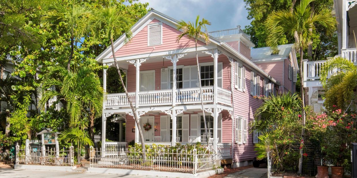 Pink two-story house with white trim and palm trees.