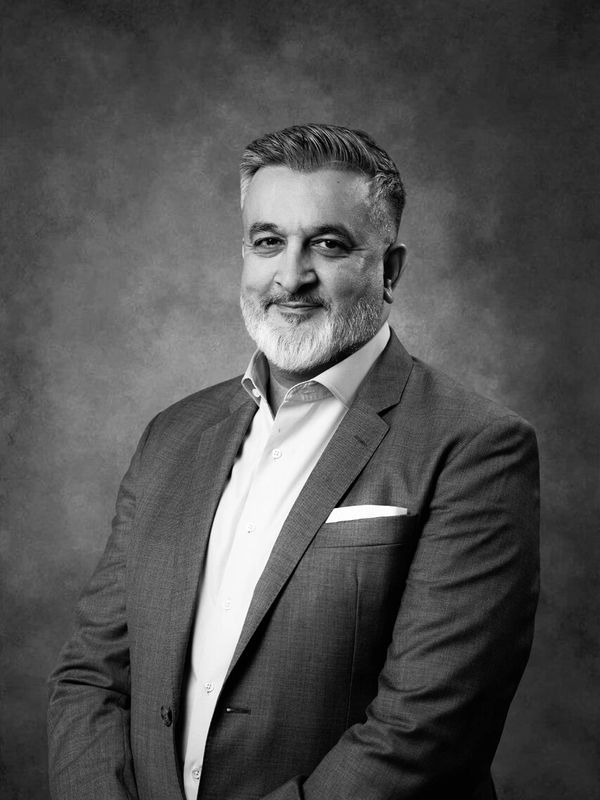 Confident man in a suit smiling against a textured backdrop.