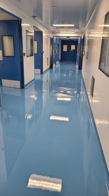 Shiny blue hallway with closed doors and reflective floor.