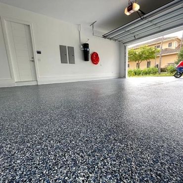 Clean garage with a speckled epoxy floor and open door.