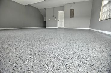 Empty room with speckled epoxy floor and gray walls.