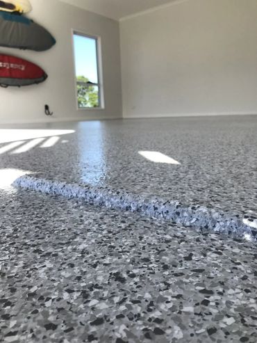 Close-up of a smooth, speckled epoxy garage floor with a raised section.