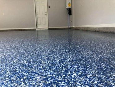 Blue and white speckled epoxy garage floor with clean walls and door.