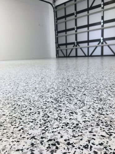 A clean garage with speckled epoxy flooring and a black-and-white garage door.