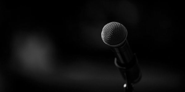 Close-up of a microphone on a stand with blue stage lighting.
