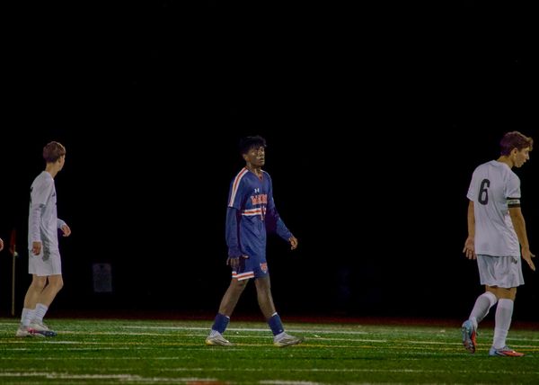 Three soccer players on the field during a night game.