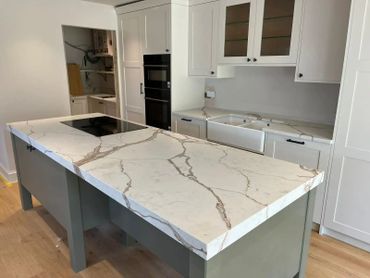 Modern kitchen with white marble countertops and gray cabinetry.