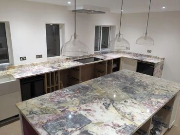 Modern kitchen with marble countertops and glass pendant lights.