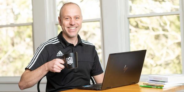 Man smiling with coffee mug by laptop.