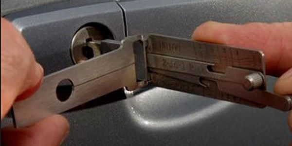 A person using a specialized key tool to unlock a car door.