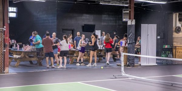 People socializing indoors near a ping pong table.