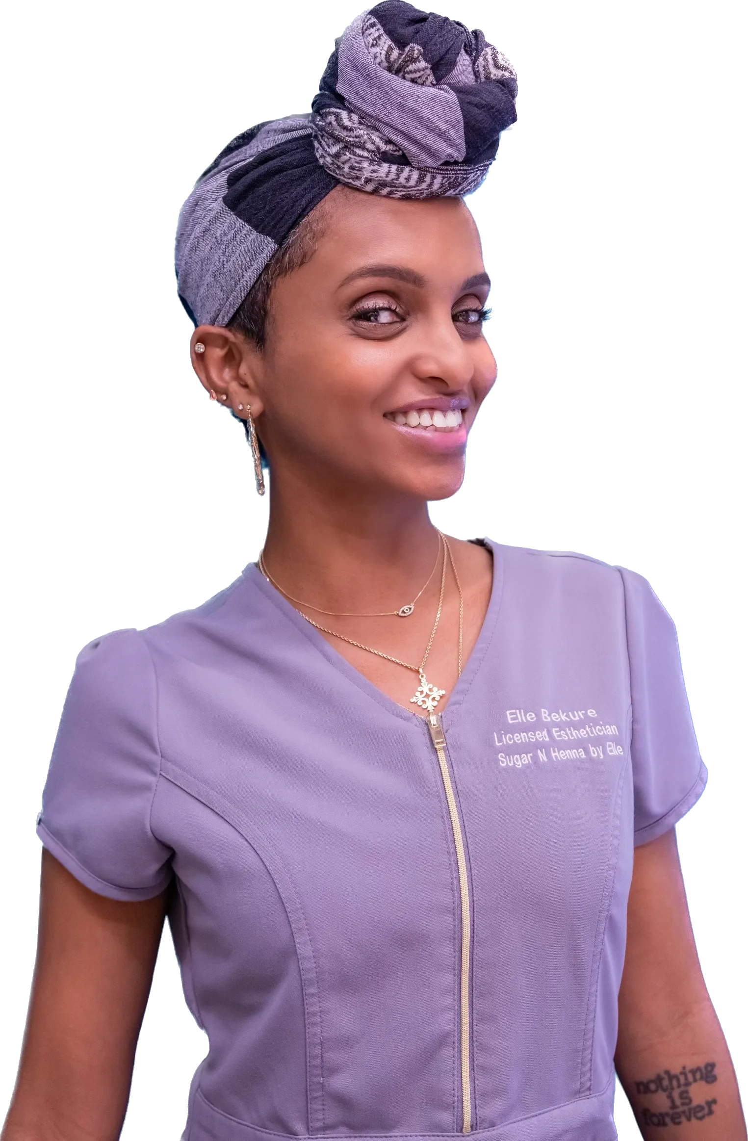 Smiling esthetician wearing a purple uniform and headwrap.