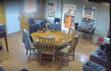 A wooden table surrounded by chairs in a cozy room with wooden floors.