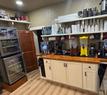 A well-organized beverage station with dispensers, cups, and refrigerators.