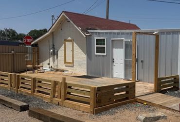 Wooden deck with a ramp and fence next to a small building.