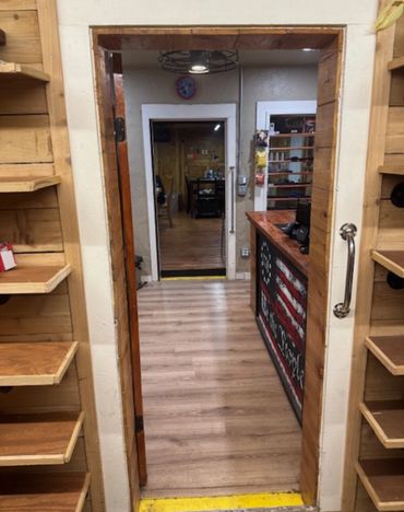 View through a wooden doorway into a room with shelves and an American flag counter.