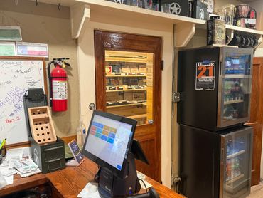 Interior of Mystery Shack Cigars & Coffee showing the checkout counter, drink coolers and humidor en