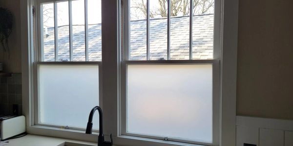 Frosted film on a residential window, providing privacy without the need for a blind or shade.