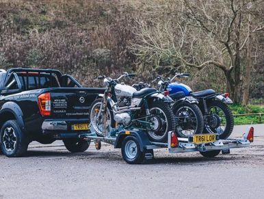 Three motorcycles loaded onto the motorbike trailer, hitched up to the Nissan Pickup truck.