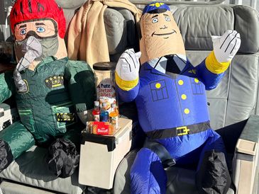 Inflatable figures dressed in military and police uniforms on airplane seats.