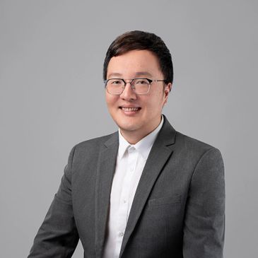 Professional portrait of a man in a gray suit and glasses.