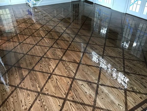 Highly polished wooden floor with a reflective surface and grid pattern.
