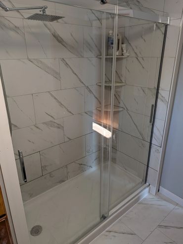 Modern shower with glass doors and marble tiles.
