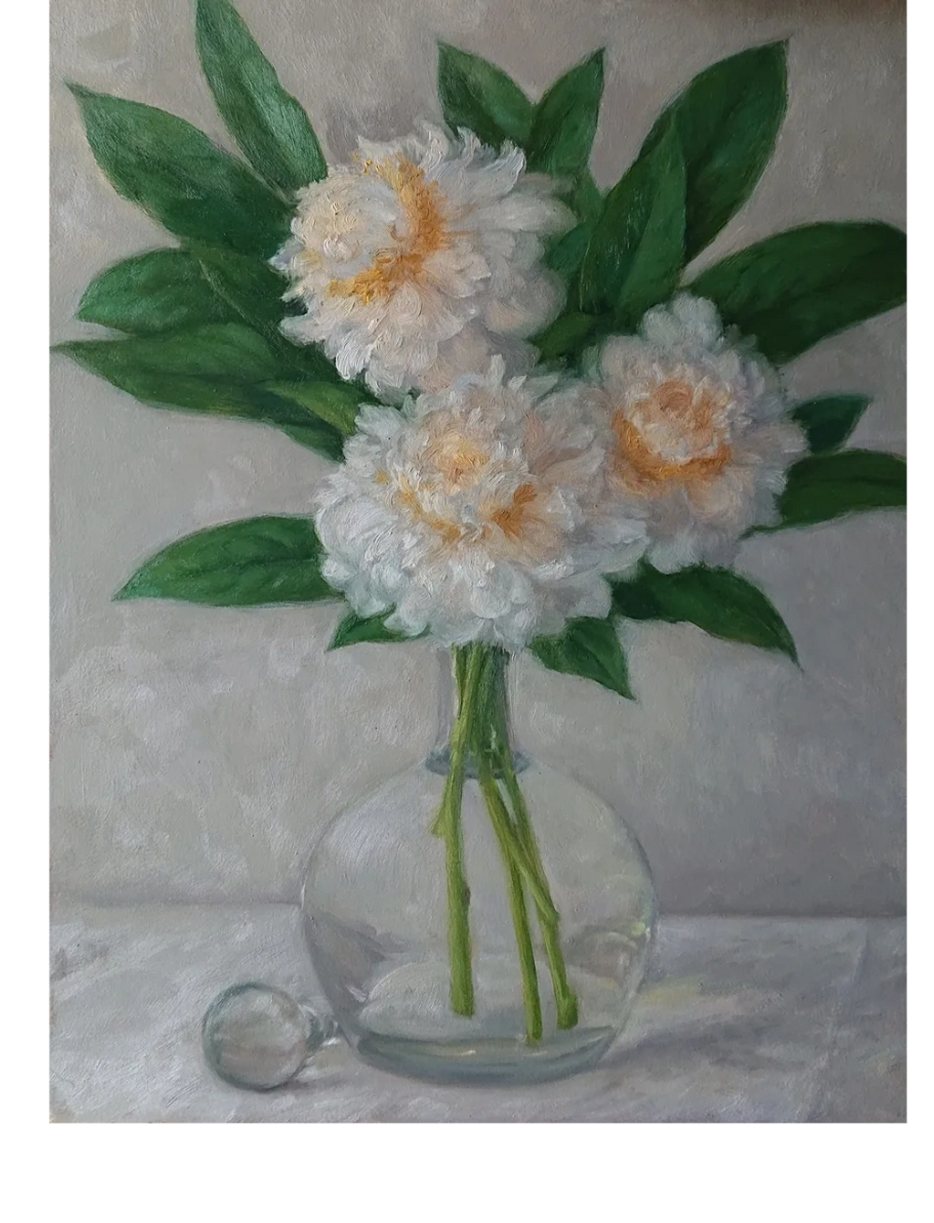 White peonies in a glass decanter on a white tablecloth.