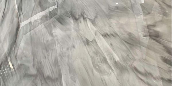 Shiny marble floor with grey and white patterns reflecting light and surroundings.