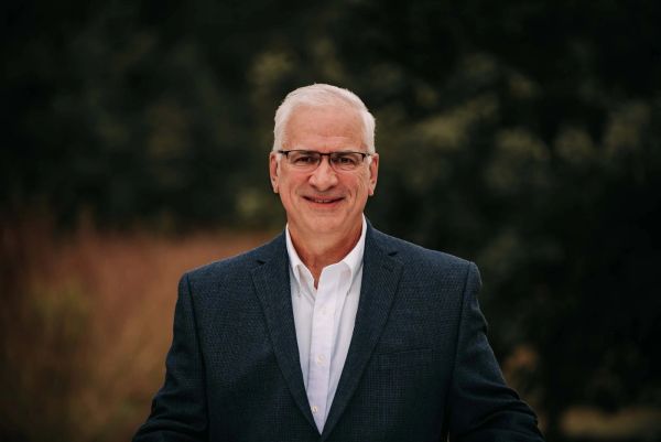 Smiling elderly man in suit and glasses.