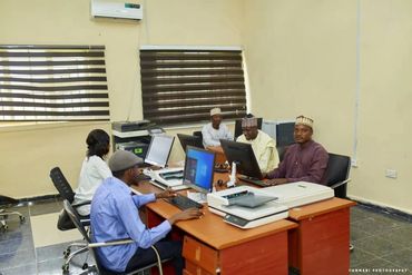 Five people working on computers in an office with modern equipment.