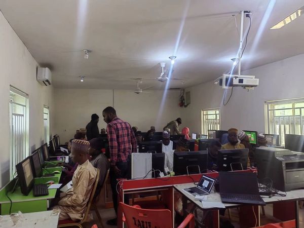 A busy computer lab with people working on desktop computers and laptops.