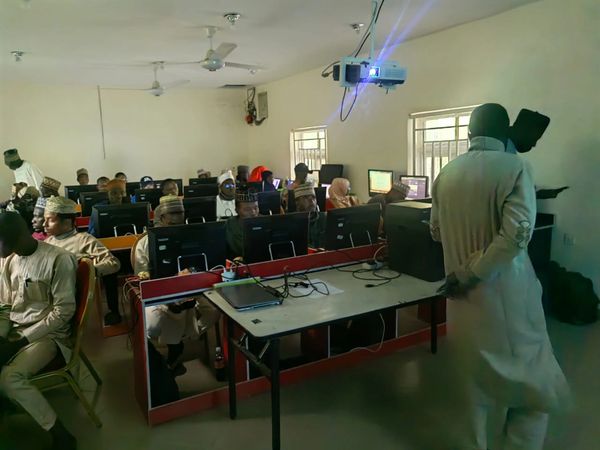 A classroom with students working on computers and an instructor at the front.