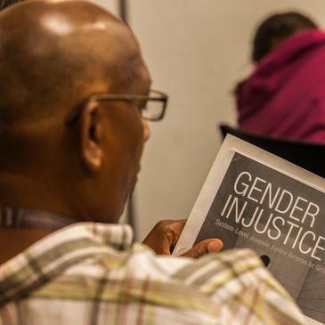 Bald, Black, African American, Man reading pamphlet on Gender Injustice at business conference