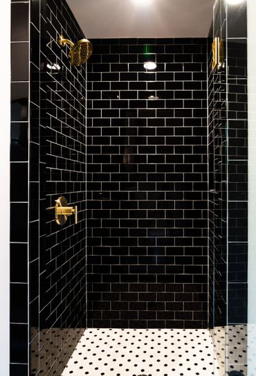 A shower wall with black, brick-like tiles