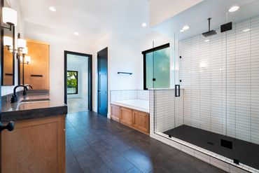 A bathroom with a glass shower area and two sinks