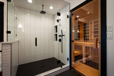 A bathroom with white wall tiles and a glass door