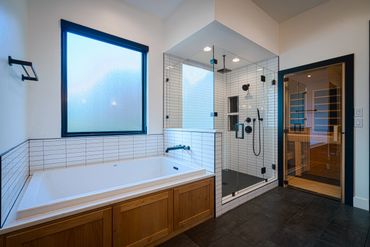 A bathtub beside the glass shower area